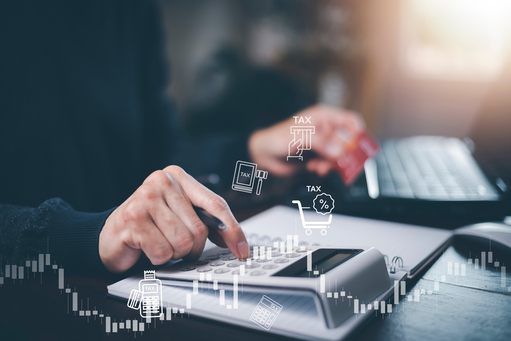 Persoană care lucrează la un laptop, analizând plăți și taxe, concept legat de TVA în Marea Britanie.