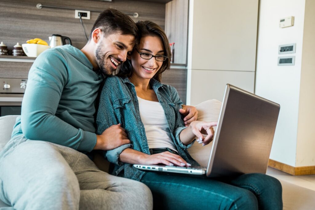 A smiling couple comparing wise v remitly on their laptop