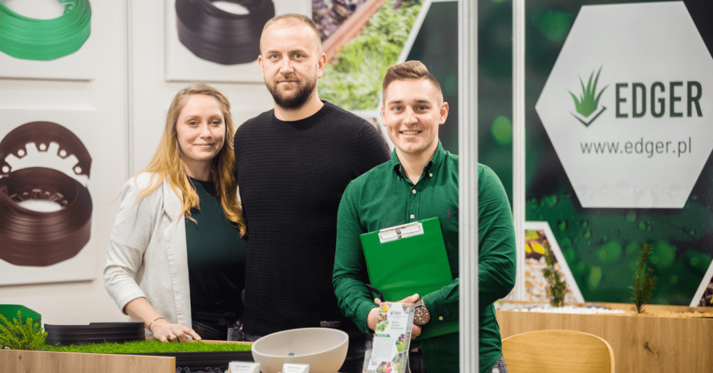 Two young men and a female smile as they face the camera and stand in front of an Edger business sign